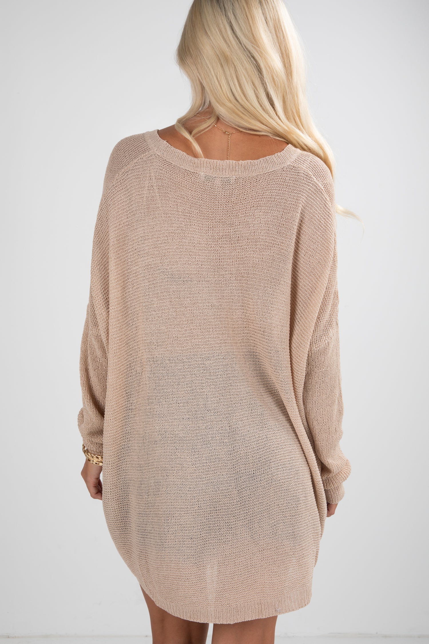 Beige sweater worn by a person on a white background