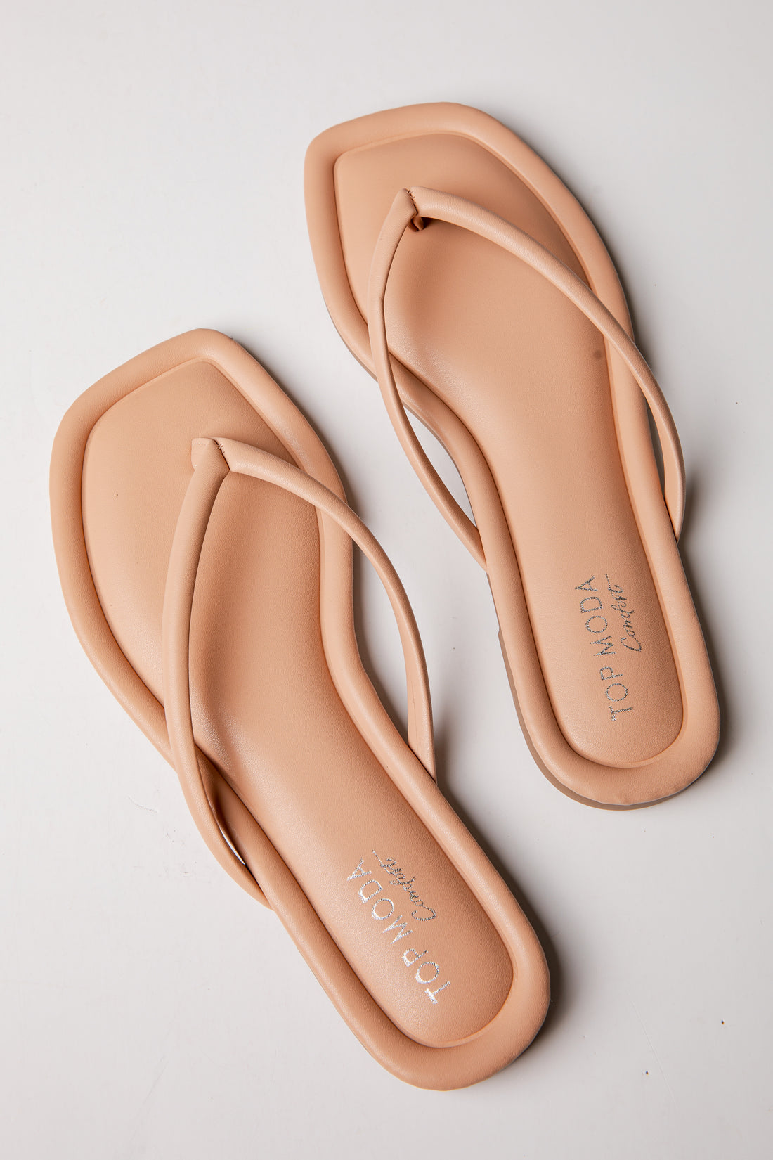 Pair of beige flip-flops on a light gray background