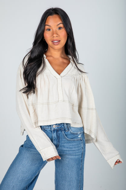 Woman wearing a white blouse and blue jeans against a plain background