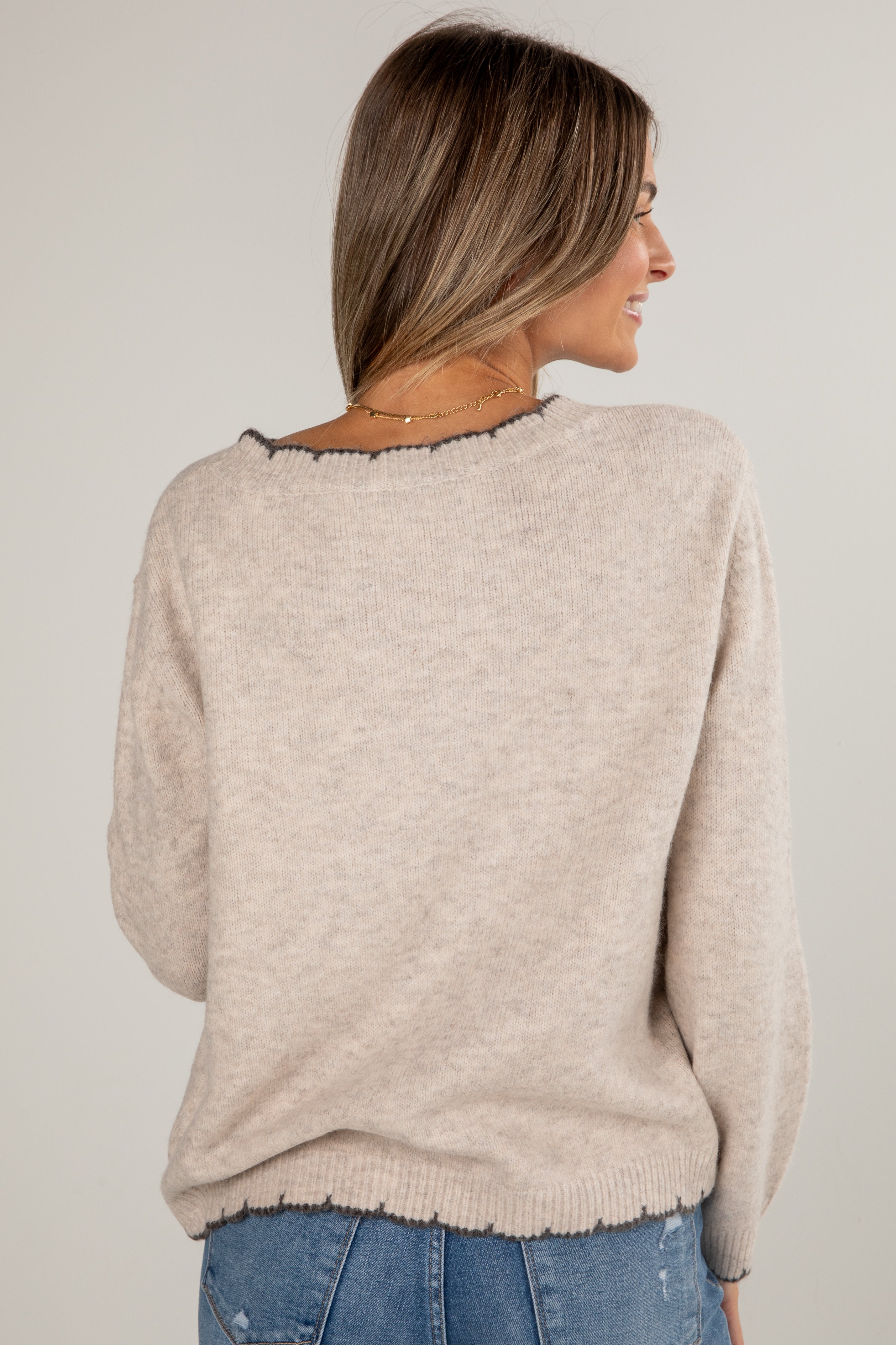 Woman wearing a beige sweater with a plain background
