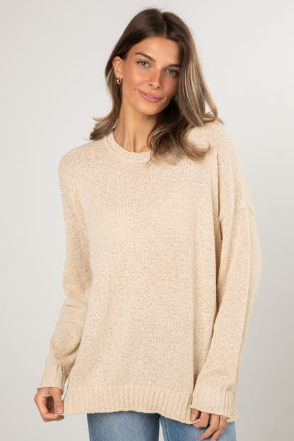 Woman wearing a beige sweater against a plain background