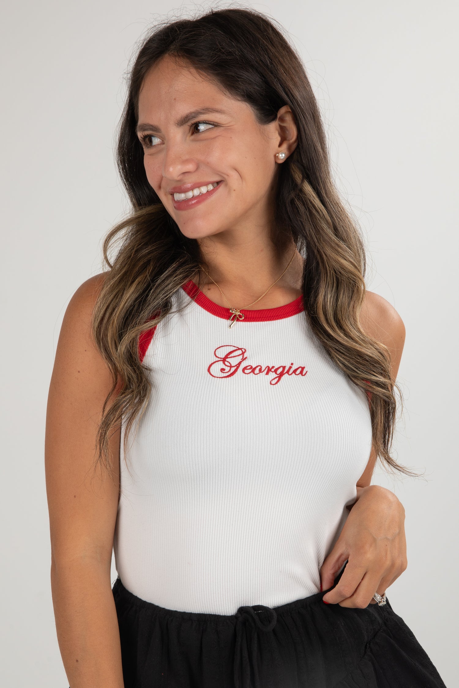 Woman wearing a white tank top with red accents and &