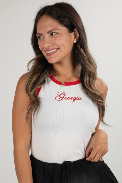 Woman wearing a white tank top with red accents and &