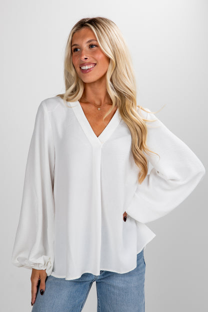 Woman wearing a white blouse and blue jeans on a plain background