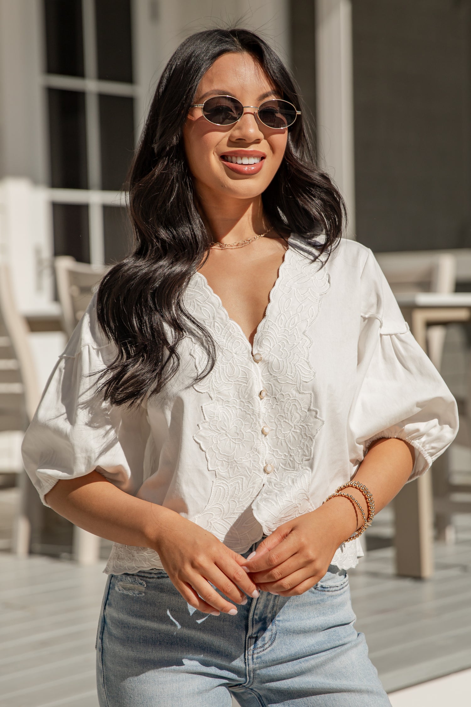 Woman wearing a white blouse and sunglasses outdoors