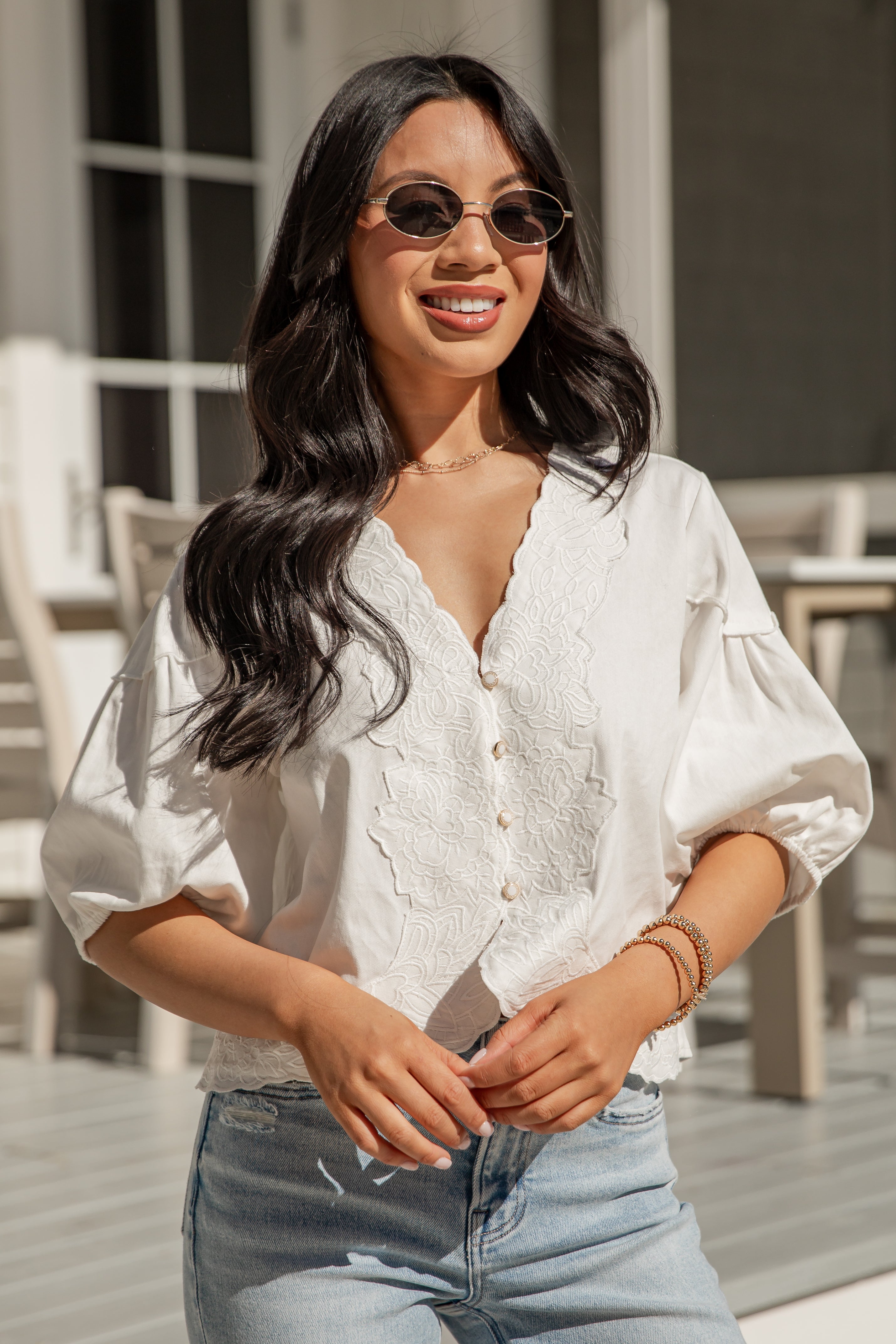Woman wearing a white blouse and sunglasses outdoors