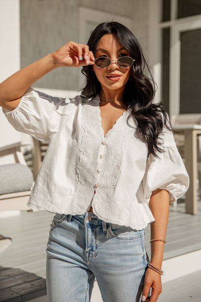 Woman wearing a white blouse and blue jeans outdoors