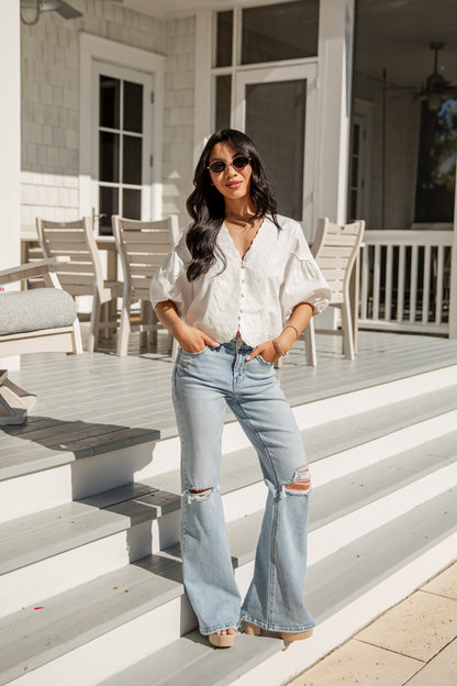 Woman in white blouse and blue jeans standing on a porch