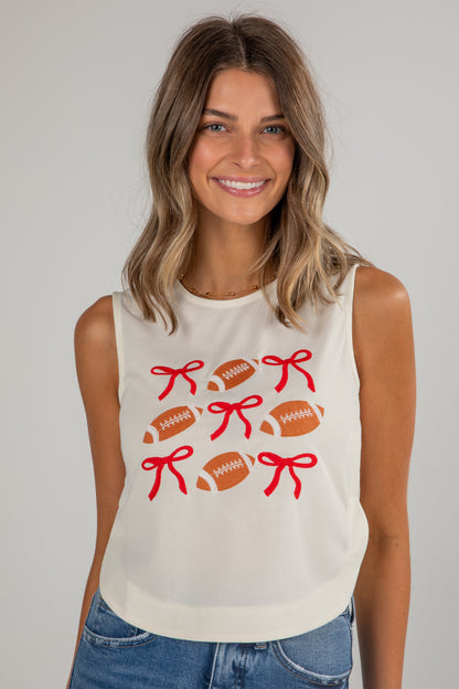 Woman wearing a sleeveless shirt with football and bow designs on a plain background