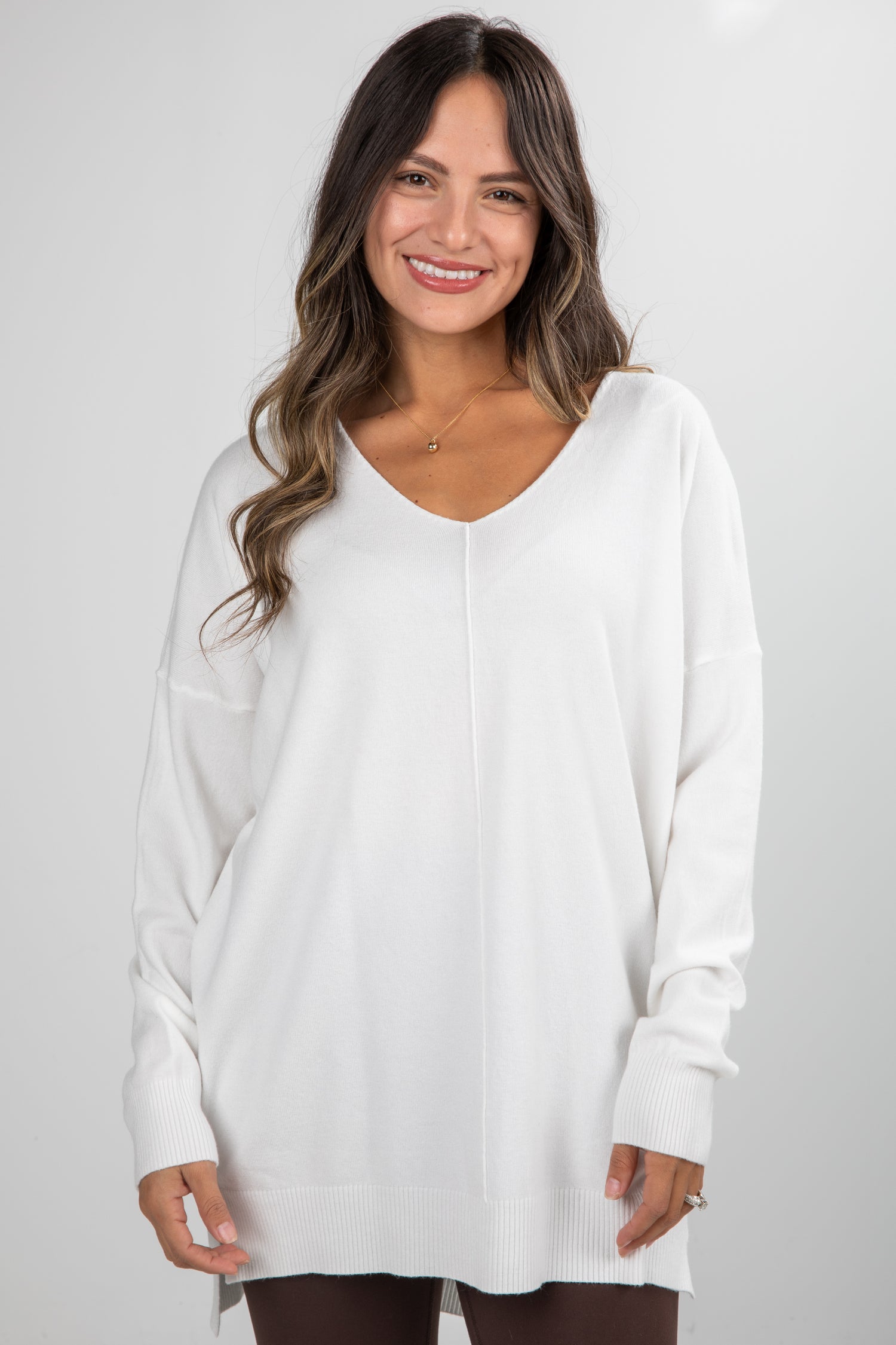 Woman wearing a white sweater against a plain background