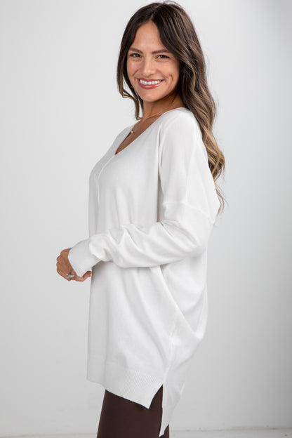 Woman wearing a white long-sleeve top against a plain background