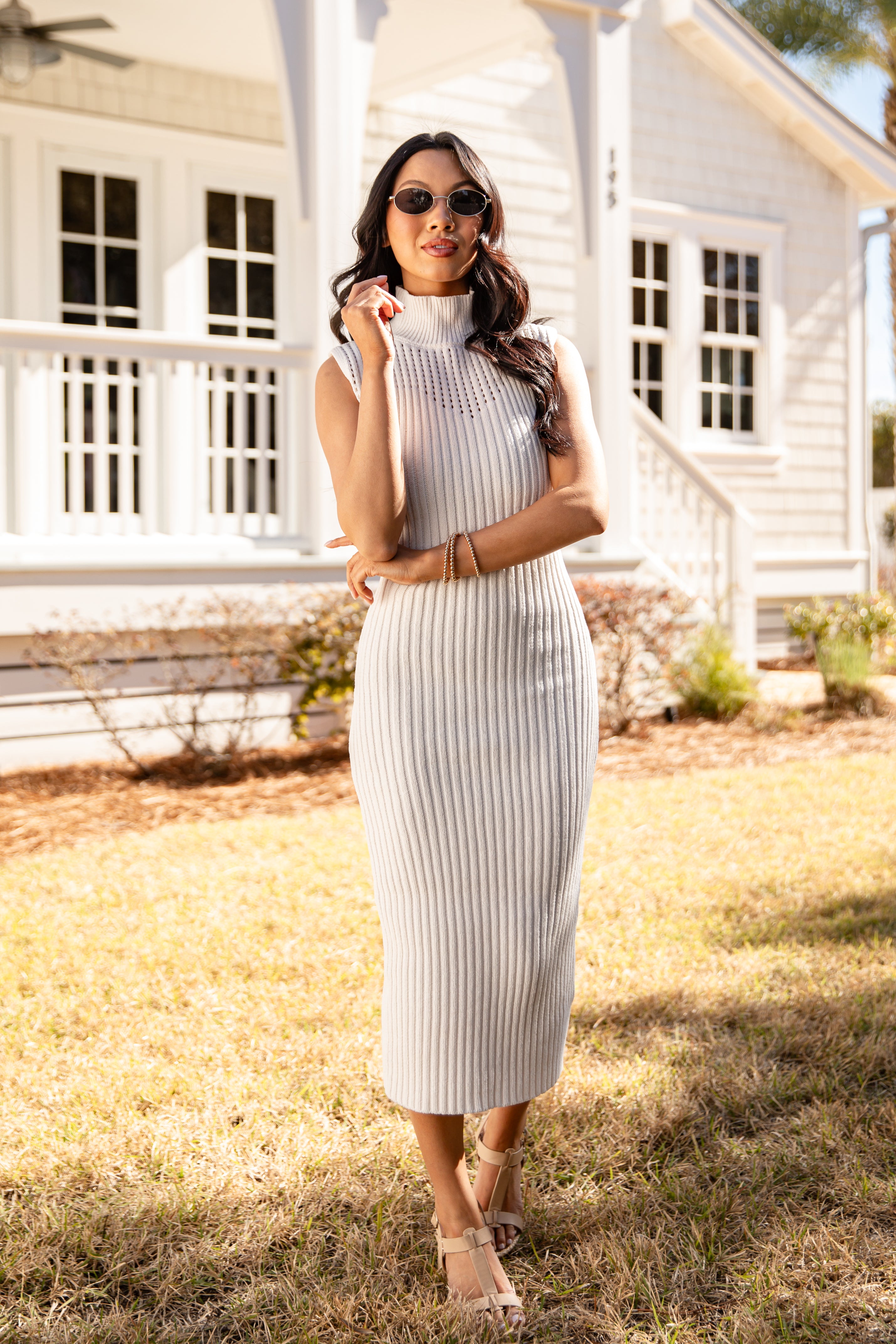 Woman in a striped dress standing in front of a white house.