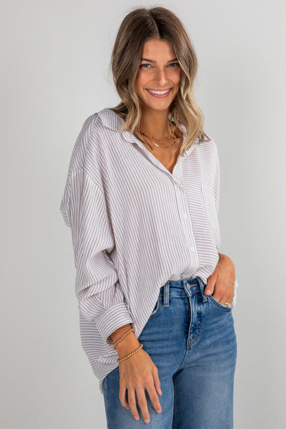 Woman wearing a striped shirt and jeans on a plain background