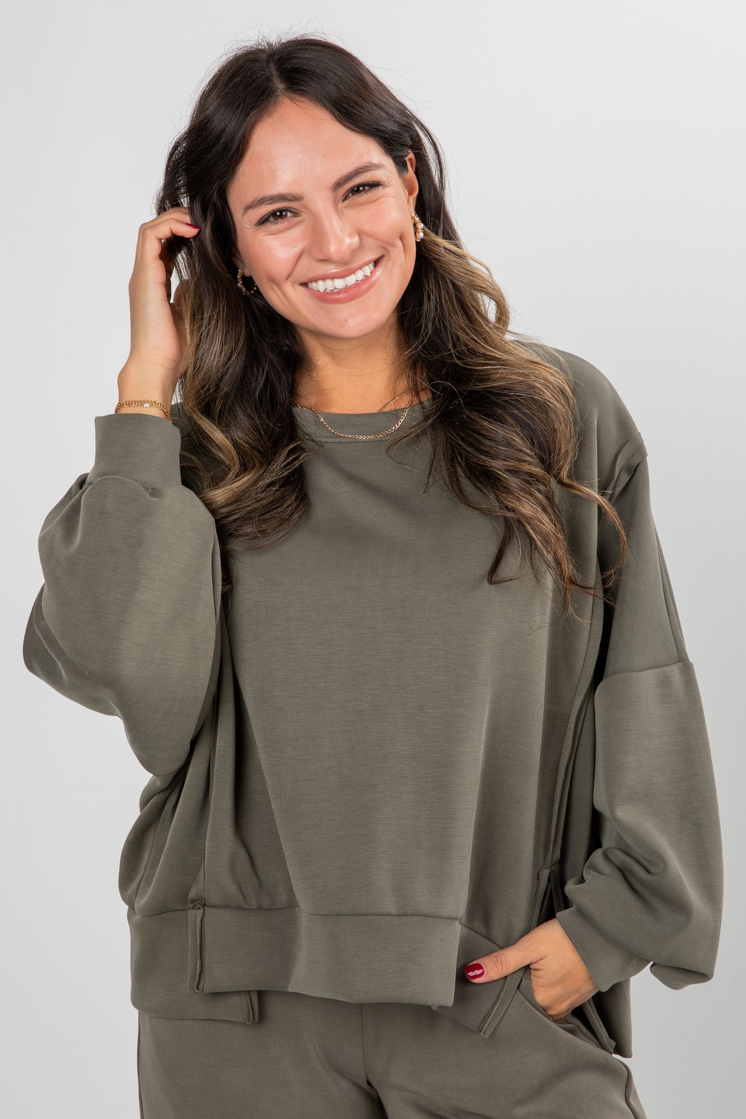 Woman wearing an olive green sweatshirt and pants against a white background