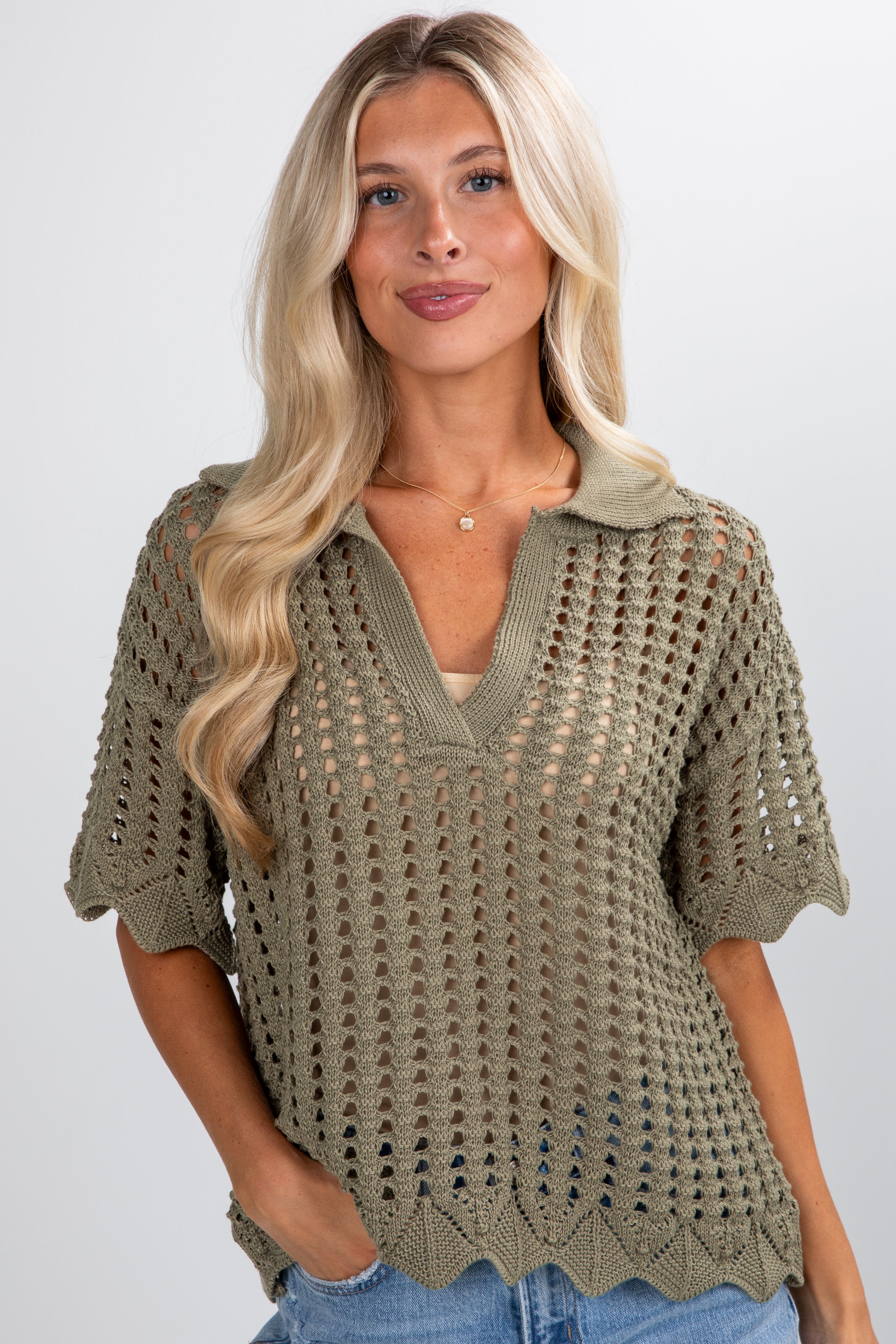 Woman wearing a green crochet top against a plain background