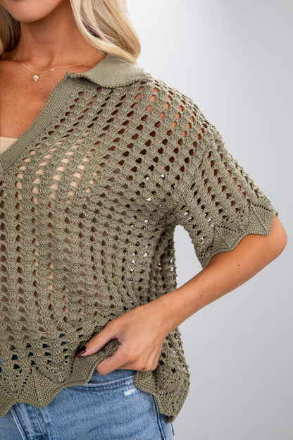 Woman wearing a green crochet top with a plain background