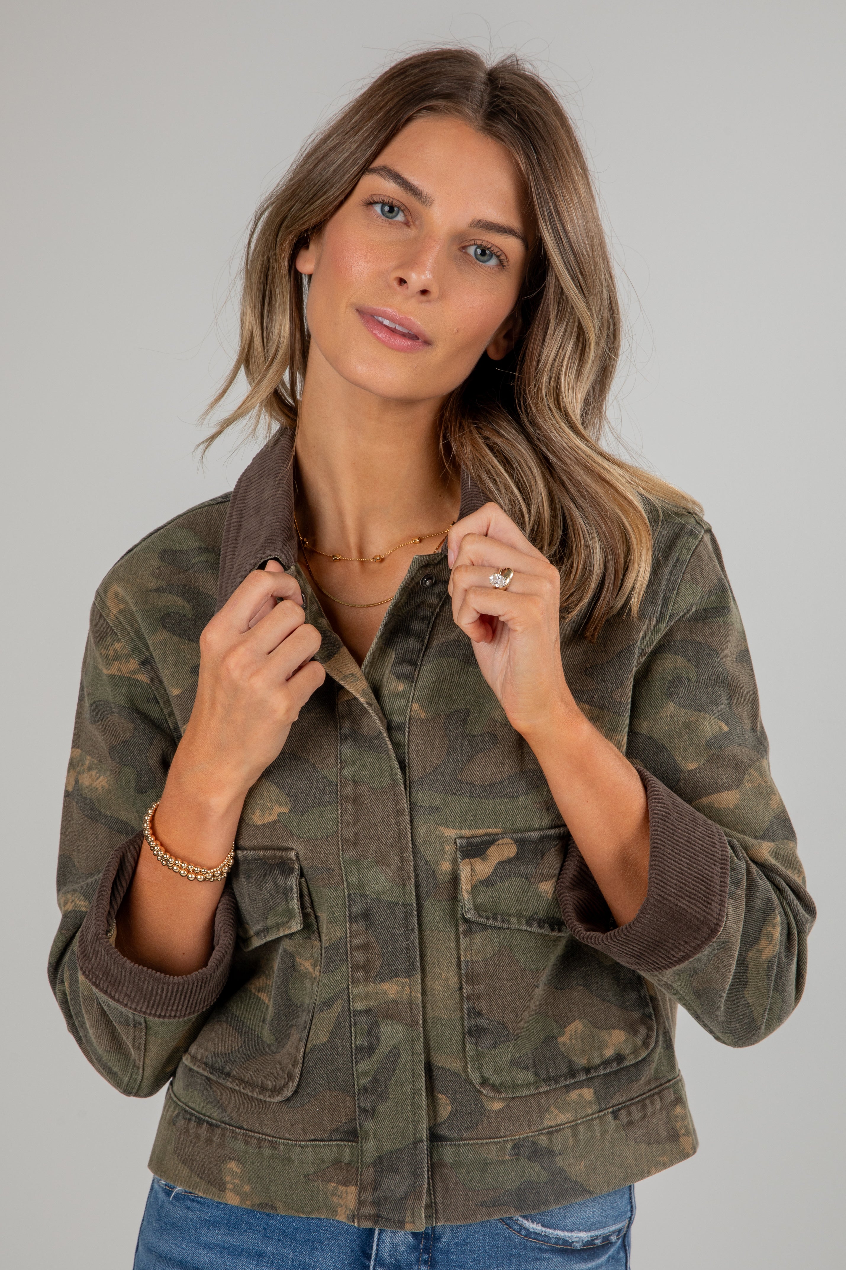 Woman wearing a camouflage jacket on a plain background