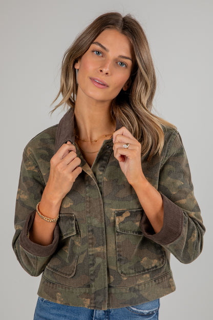 Woman wearing a camouflage jacket on a plain background