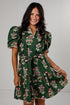 A woman modeling a dark green short-sleeve mini dress with a pink and beige floral print, featuring puff sleeves, a V-neckline, and a matching fabric tie belt.