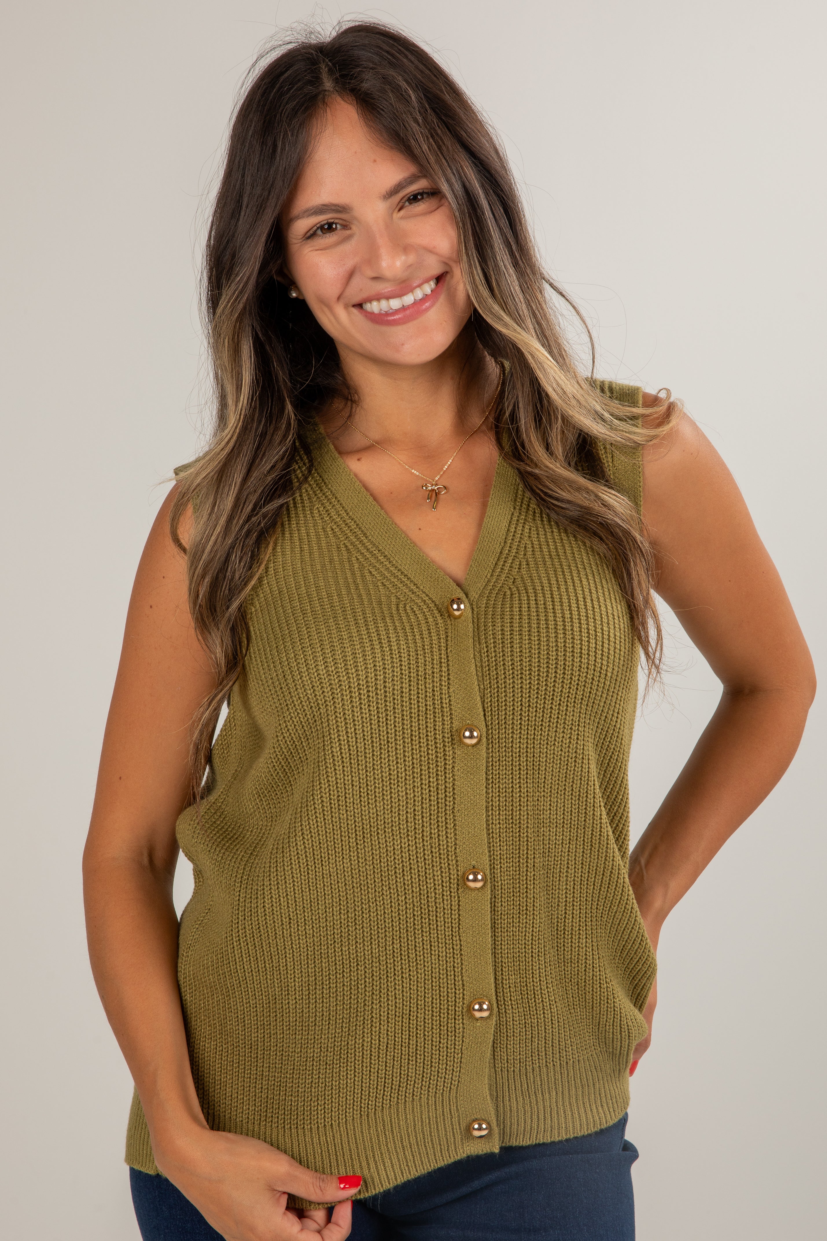 Woman wearing a green sleeveless button-up top against a plain background