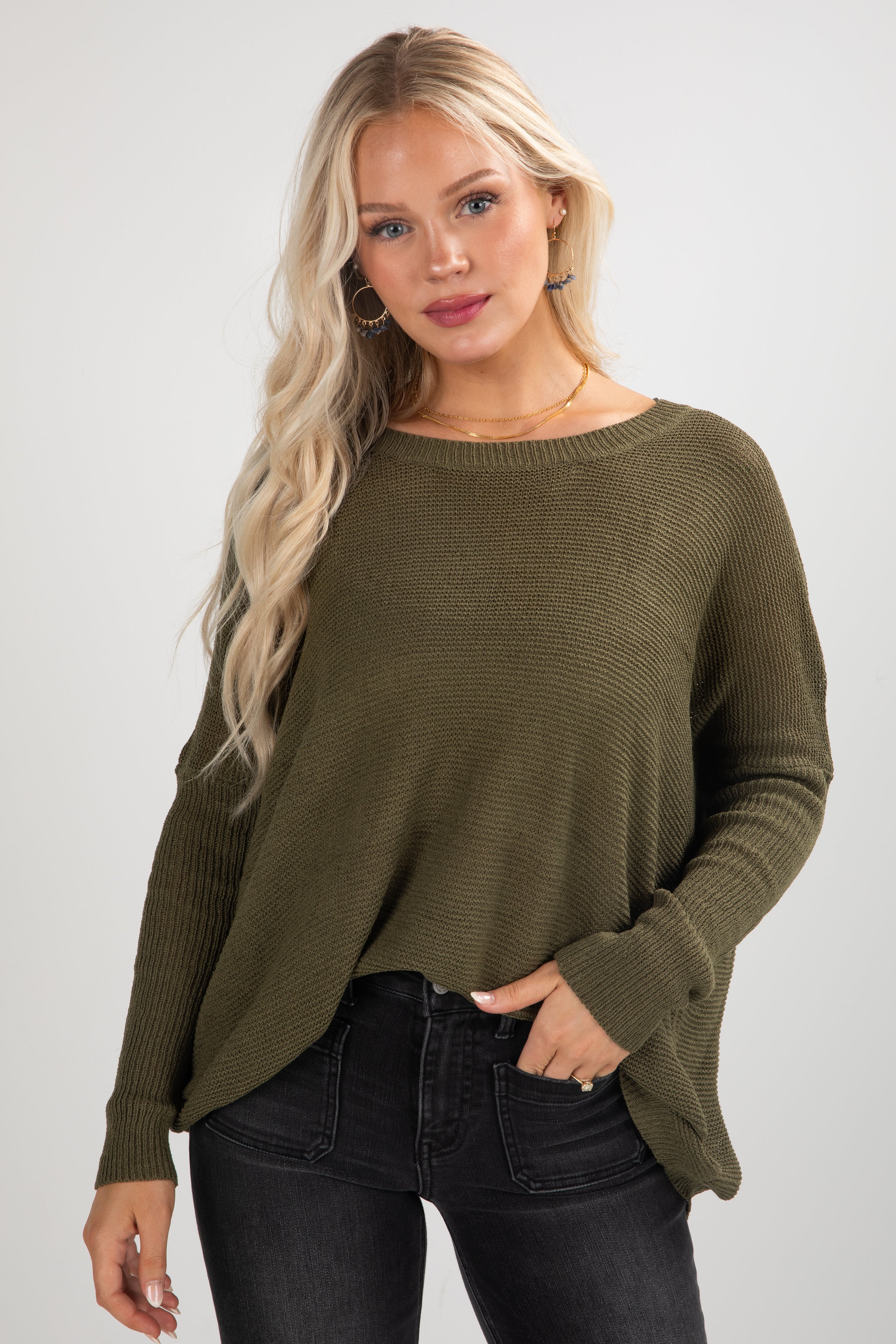Woman wearing an olive green sweater against a plain background