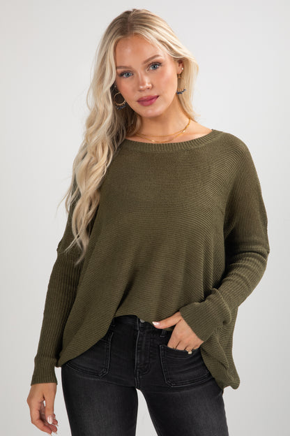 Woman wearing an olive green sweater against a plain background