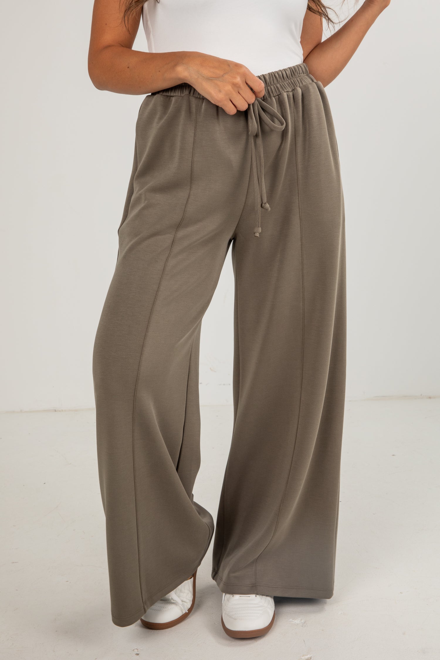 Person wearing brown wide-leg pants on a white background