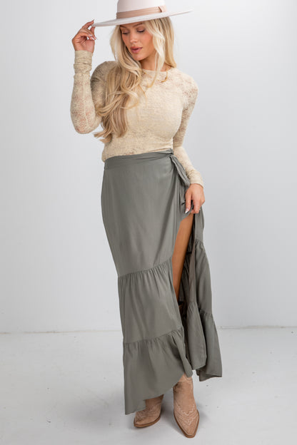 Woman wearing a beige sweater and gray skirt with a white background