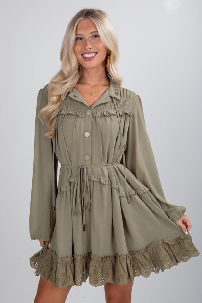 Woman wearing a green dress with long sleeves and ruffled details on a white background