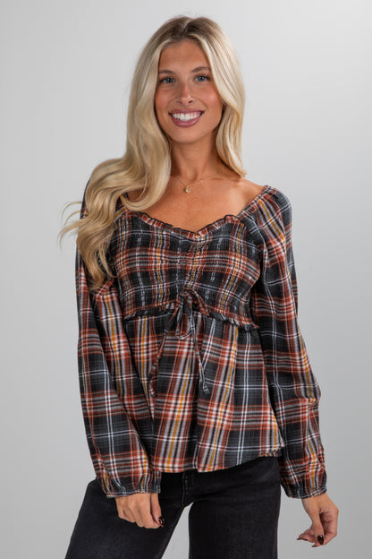 Woman wearing a plaid top against a plain background
