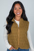 Woman wearing a brown quilted vest against a plain background