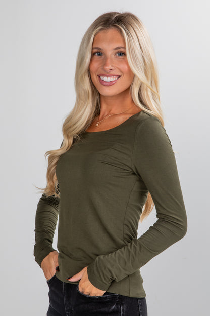 Woman wearing an olive green long-sleeve top against a plain background