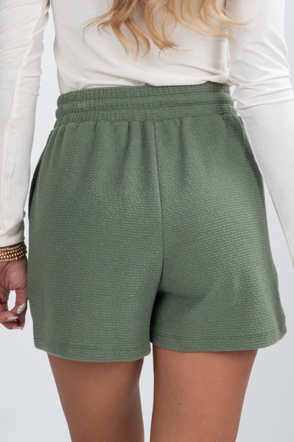 Green shorts worn by a person on a white background