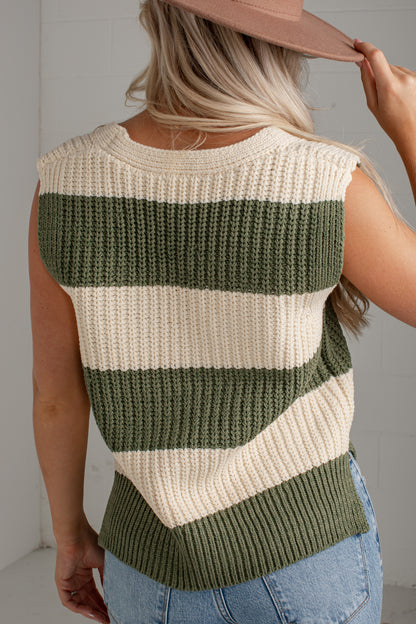 A woman shown from the back wearing a sleeveless ribbed knit sweater vest with horizontal stripes in olive green and cream, paired with light blue jeans and a dusty pink hat.