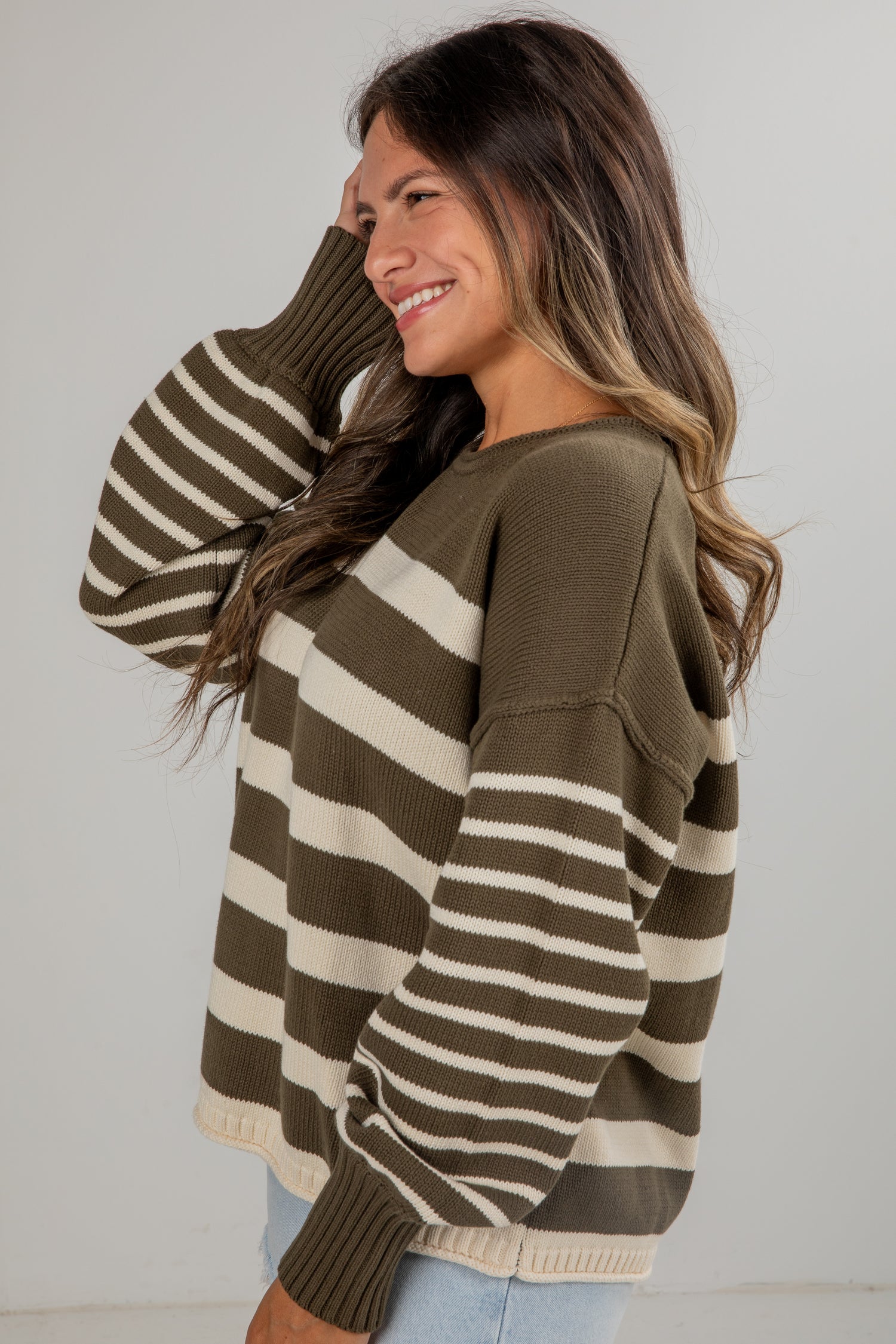 Woman wearing a brown and beige striped sweater against a plain background