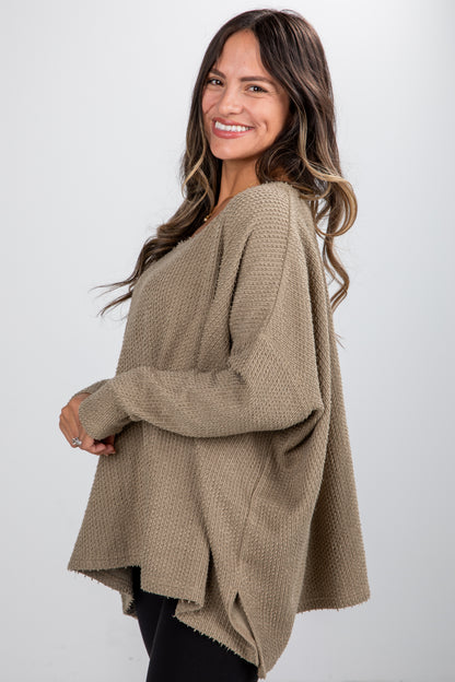 Woman wearing a beige sweater against a white background