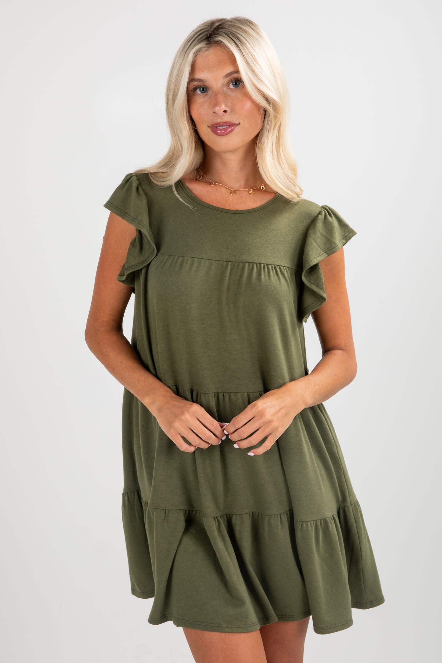 Woman wearing an olive green dress with ruffled sleeves on a white background