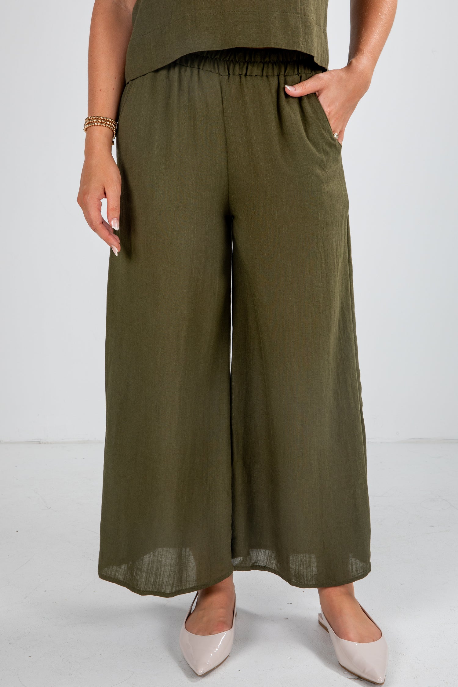 Person wearing olive green wide-leg pants on a white background