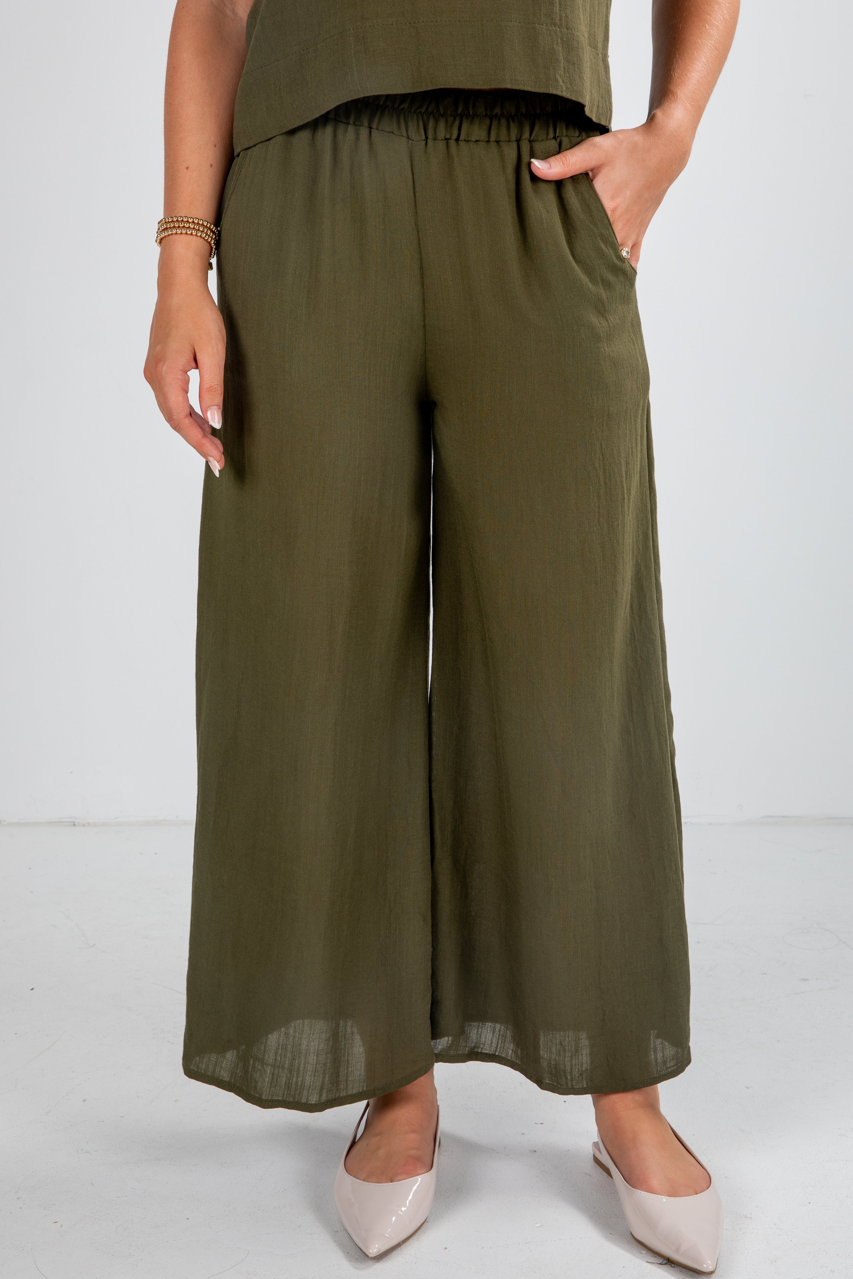 Person wearing olive green wide-leg pants on a white background