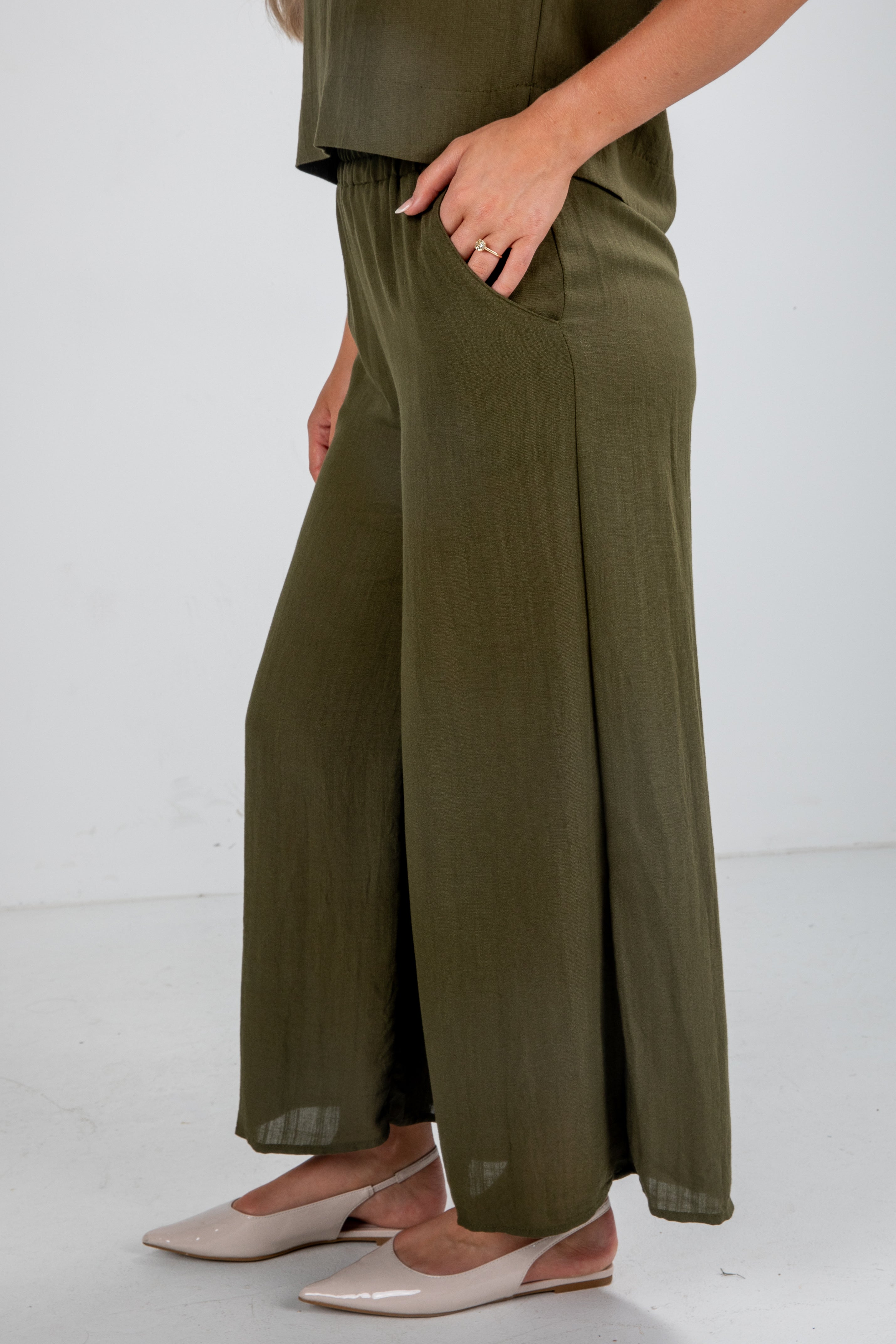 Person wearing olive green wide-leg pants on a white background