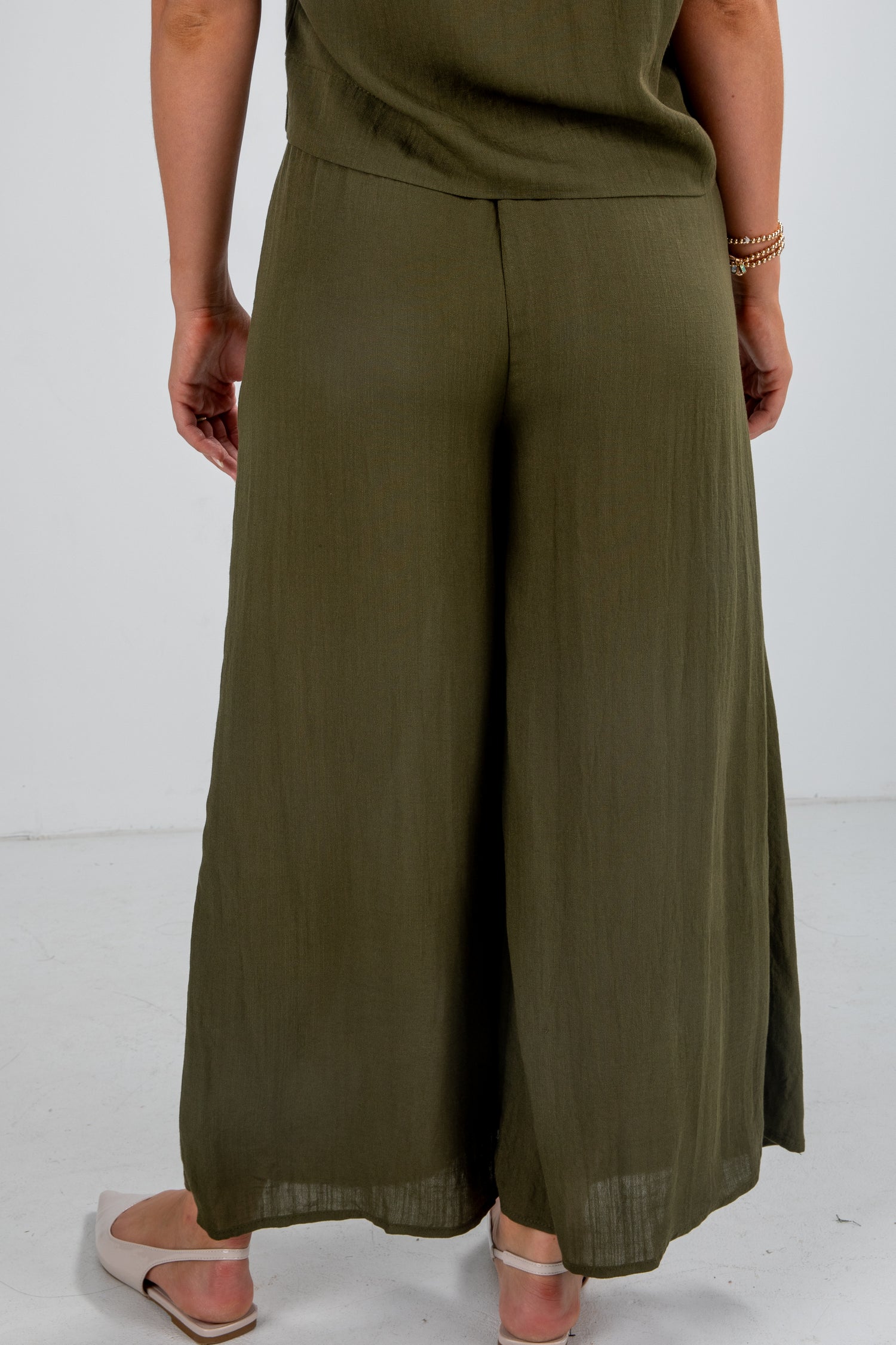 Person wearing olive green wide-leg pants on a white background