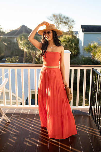Woman in a red dress and hat on a balcony