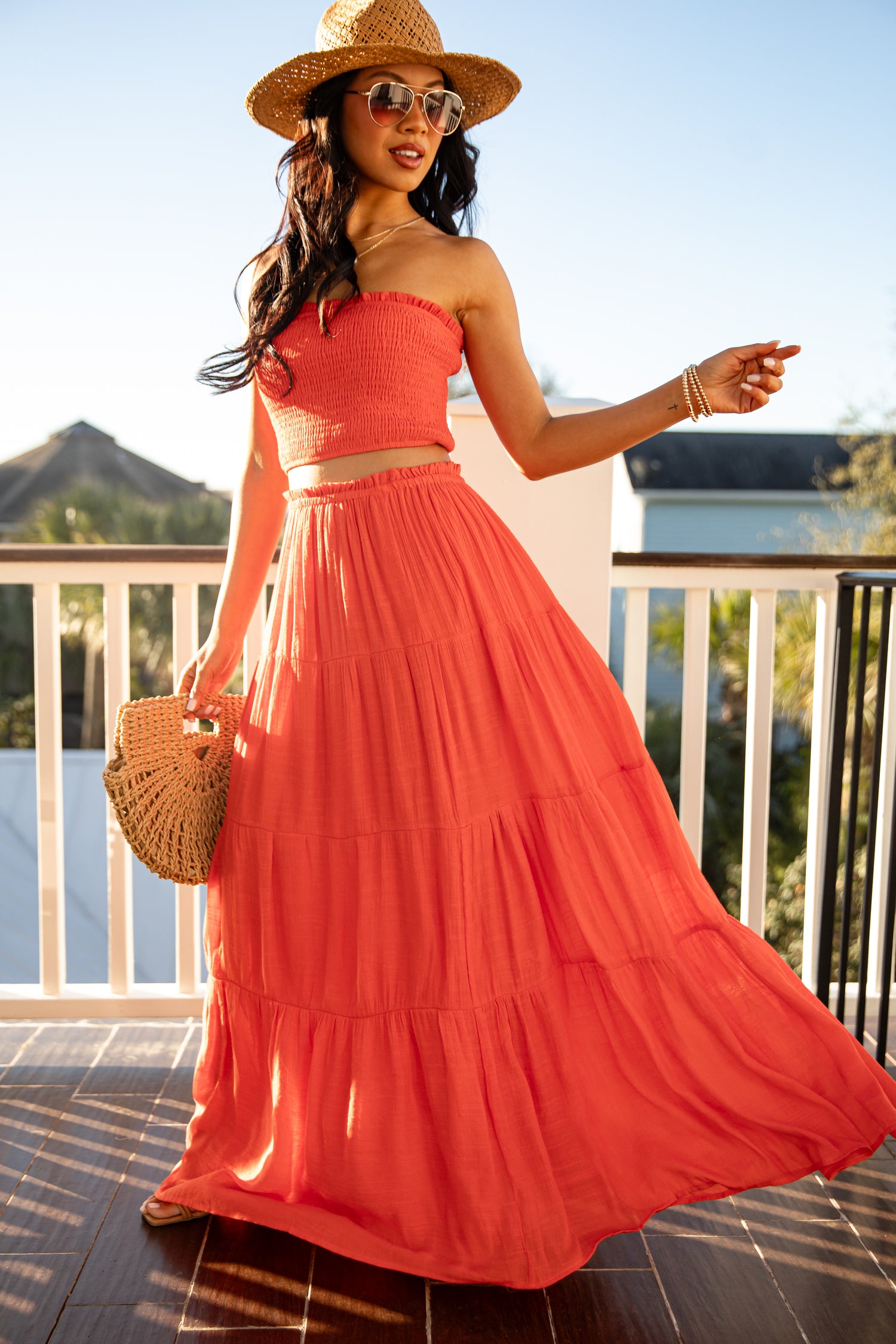 Woman in a coral dress and hat on a balcony