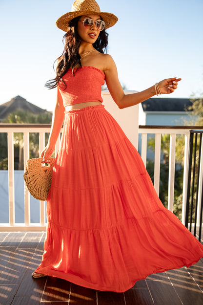 Woman in a coral dress and hat on a balcony