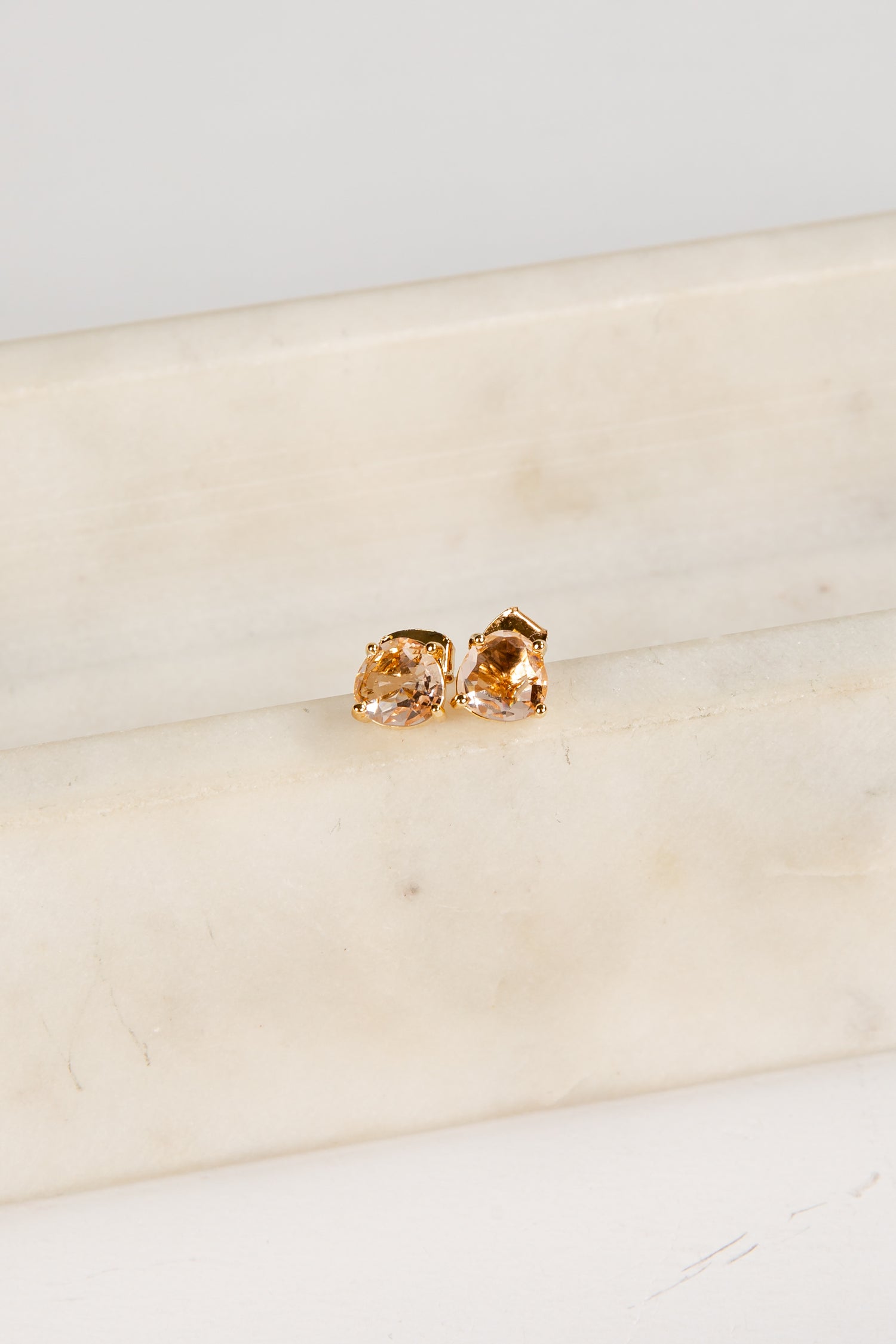 Gold earrings on a marble surface