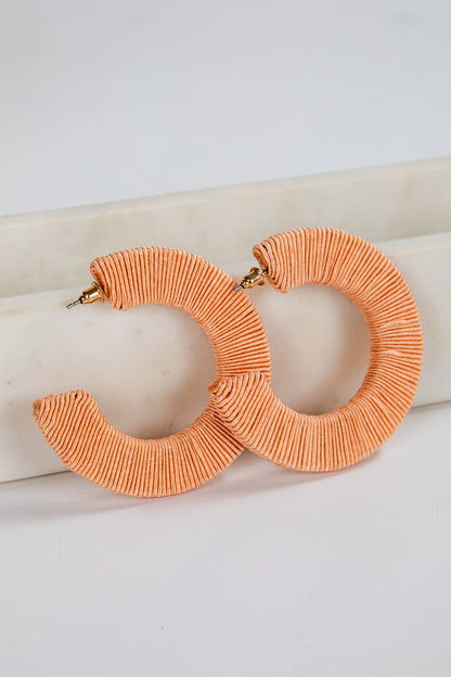Pair of orange hoop earrings on a white surface