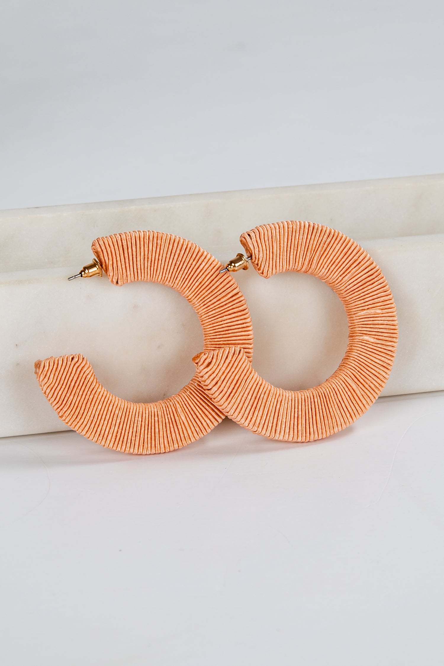Pair of orange hoop earrings on a light background