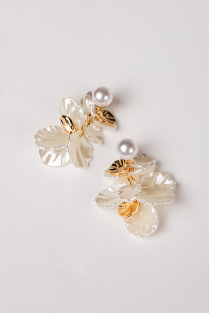 Pair of floral earrings with pearls on a light gray background