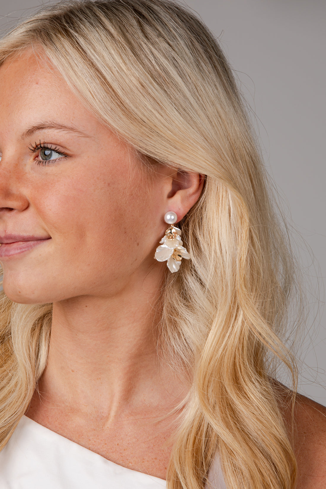 Close-up of a woman wearing pearl earrings with a neutral background