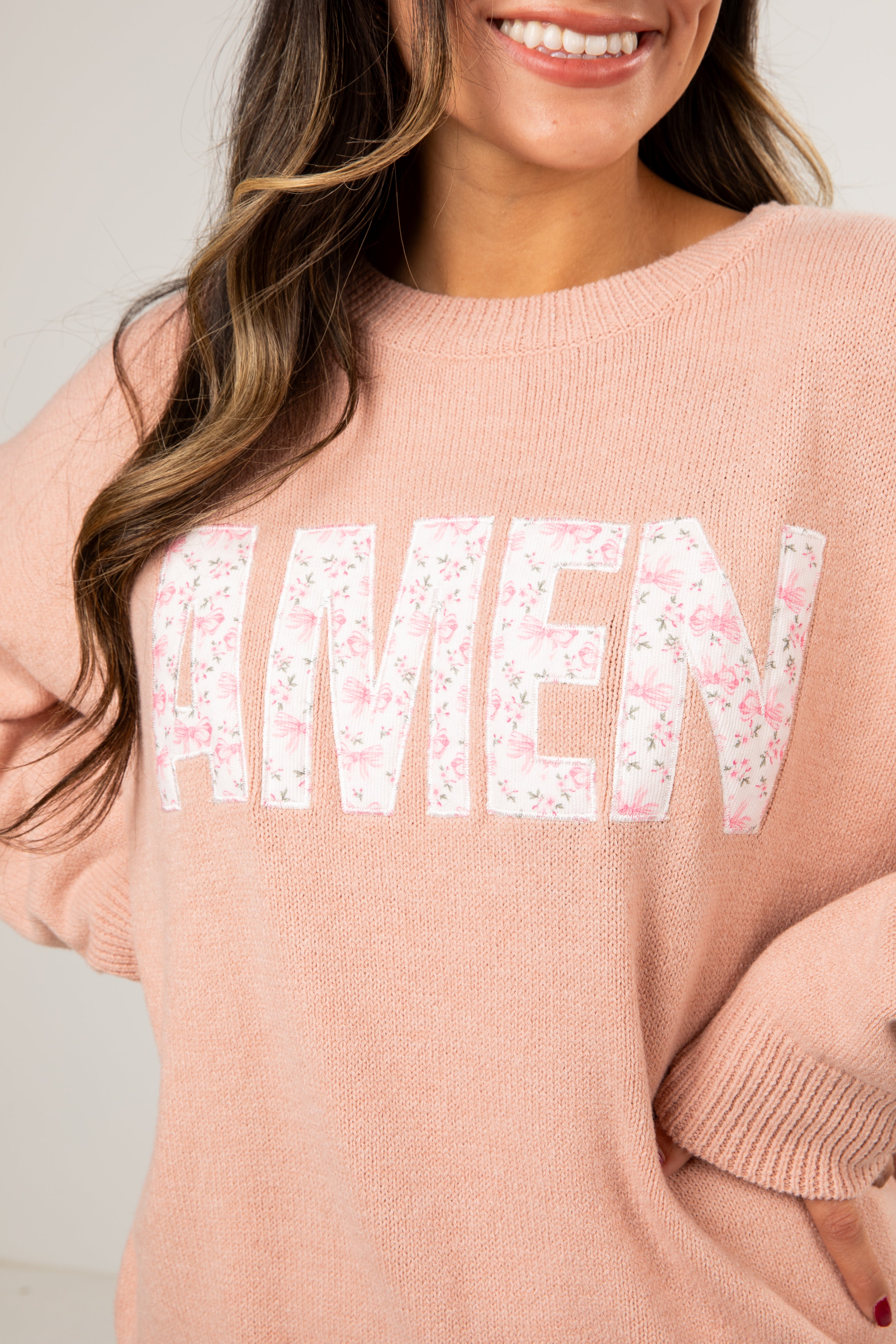 Person wearing a pink sweater with &